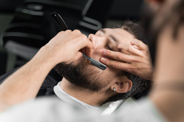 Parturi leikkasi parran parturissa. Barber mies tekee kampauksen komea mies - Valokuva, kuva