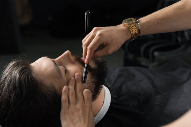 Coupe droite rasoir mans barbe dans le salon de coiffure. Barbier homme faisant coiffure pour bel homme - Photo, image
