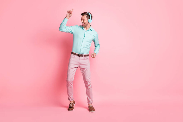 Full size photo of young crazy smiling cheerful man dancing listen music in headphones isolated on pink color background - Фото, изображение