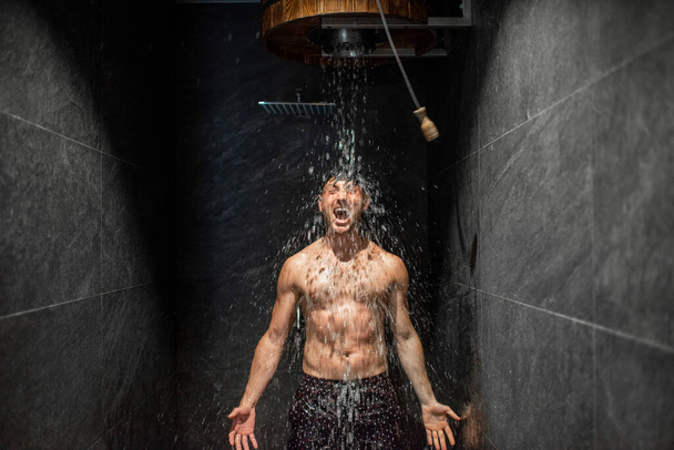 Man verhardend met emmer ijskoud water na hete sauna - Foto, afbeelding