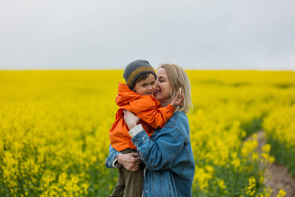 Blonde mother with a son on rapeseed field - Фото, зображення