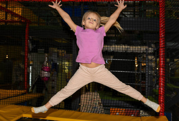 Gyermek lány ugrál egy trambulinon a játszóházban. - Fotó, kép