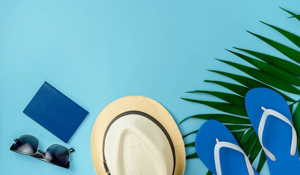 Reizigers accessoires en palmblad op blauwe achtergrond. Bovenaanzicht, kopieer ruimte. - Foto, afbeelding