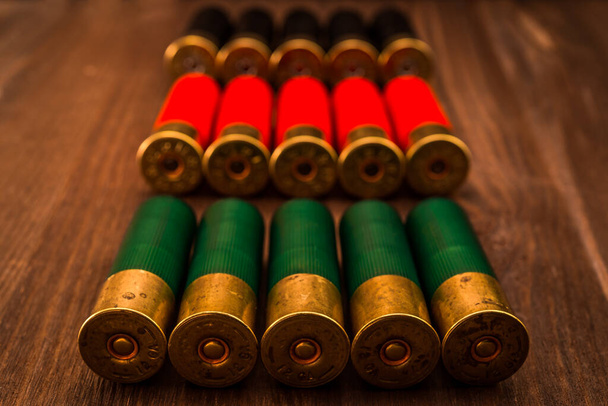 Three rows of 12 gauge cartridges lying on a wooden table. - Fotó, kép