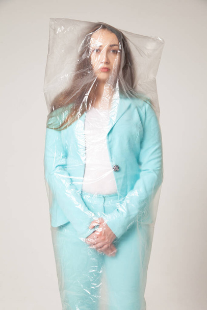 Stylish woman in plastic bag against gray background - Valokuva, kuva