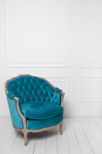 armchair in turquoise color of the Baroque style against the background of a white wall on a white floor in the interior - Photo, Image