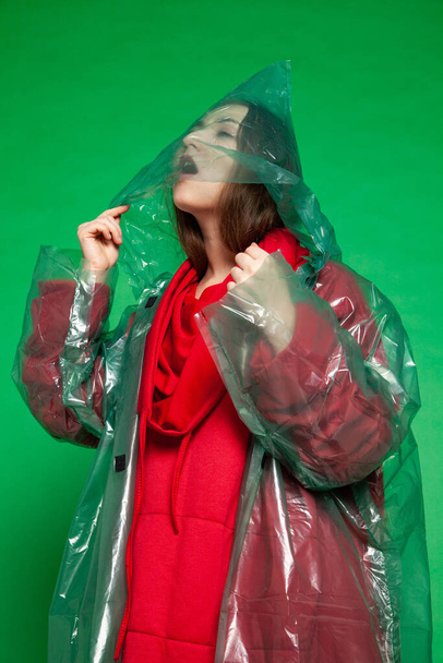Woman in green raincoat in studio on green background - Photo, image