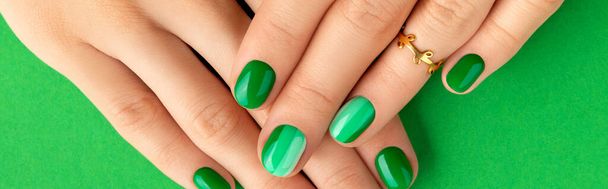 Schöne gepflegte Frauenhände mit Frühling Sommer Nageldesign auf grünem Hintergrund - Foto, Bild