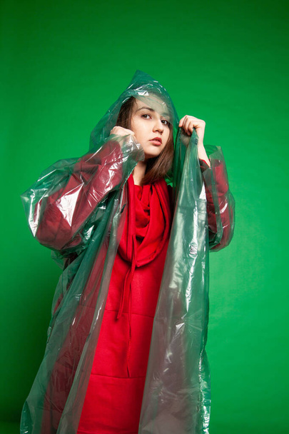 Woman in raincoat standing in studio on green background - Foto, immagini