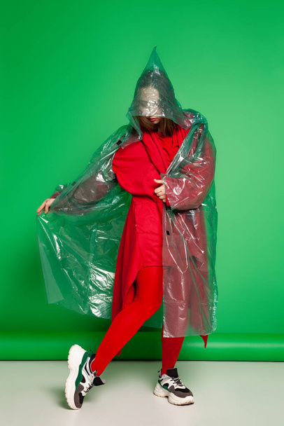 Woman in raincoat standing in studio on green background - Foto, imagen