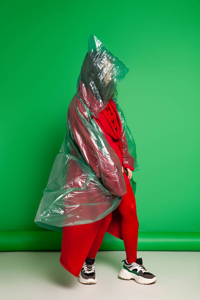 Woman in raincoat standing in studio on green background - Foto, Bild