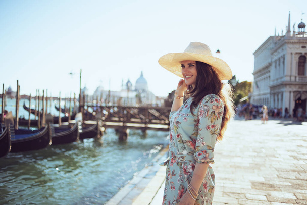 happy stylish woman in floral dress with hat exploring attractions on embankment in Venice, Italy. - Φωτογραφία, εικόνα