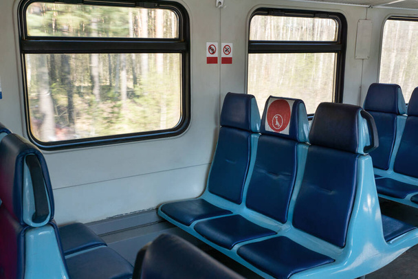 Chariot vide dans le train avec chaises bleues et autocollants ronds rouges avec restriction qui interdisent de prendre le siège du milieu dans la rangée pour réduire le nombre de passagers.. Voyager dans une nouvelle réalité, des restrictions covid - Photo, image