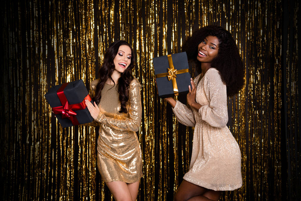 Photo of two positive carefree chic ladies hold presents dance wear glossy outfit isolated tinsel background - Photo, image