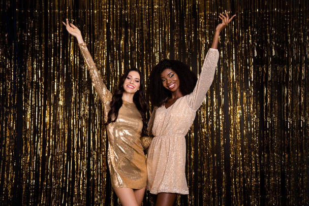 Photo of young happy cheerful smiling good mood girls enjoying party wear shiny dress isolated on glittered background - 写真・画像