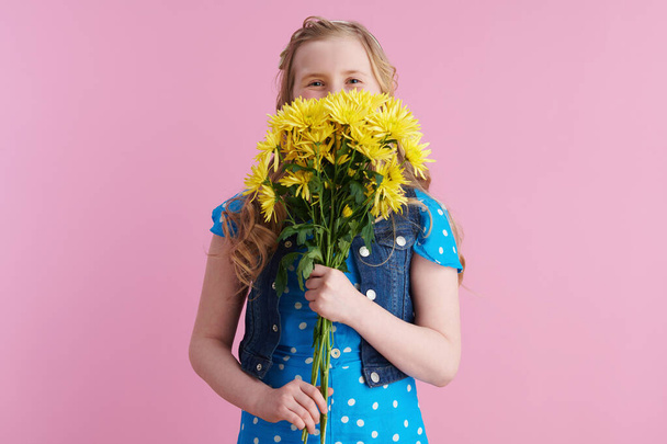 šťastná moderní dívka s dlouhými vlnitými blond vlasy se žlutými chryzantémy květiny izolované na růžové. - Fotografie, Obrázek