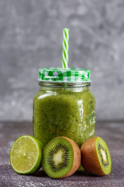 Healthy fresh fruit smoothie drink surrounded by kiwi halves on a gray concrete background. The concept of a healthy lifestyle and proper nutrition. Vitamin drink. - Valokuva, kuva