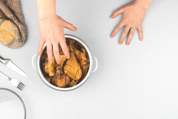 Hongerig kind trekt zijn hand voor voedsel, concept, gebraden kip in een pan, keuken werkruimte achtergrond, bovenaanzicht en kopieer ruimte foto - Foto, afbeelding