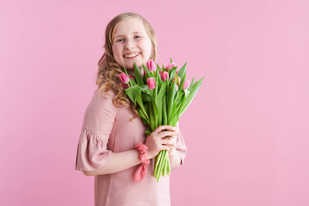 smiling stylish girl with long wavy blond hair with tulips bouquet isolated on pink background. - Foto, Bild