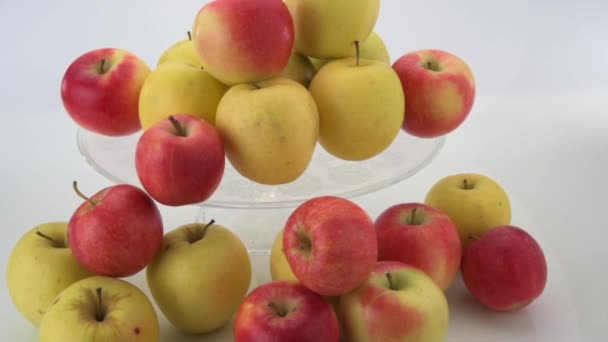 maçãs fuji e maçãs douradas em placa de vidro transparente levantada, frutas vermelhas e amarelas isoladas no fundo branco, pan - Filmagem, Vídeo