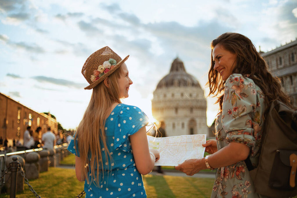 happy elegant mother and child with map and backpack sightseeing near Duomo di Pisa. - Foto, imagen