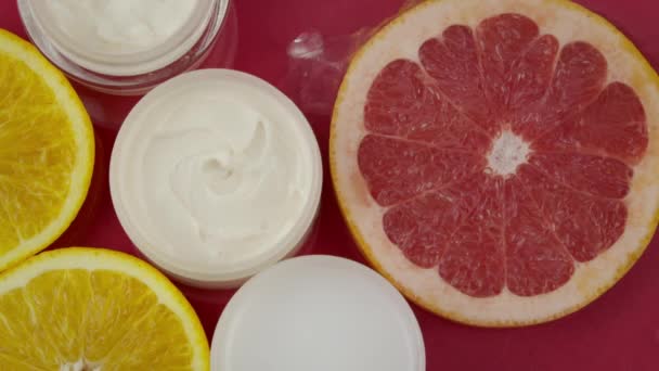 Kosmetické nádoby s hydratační krém, kousky citrusových plodů ve vodní stříkance - Záběry, video