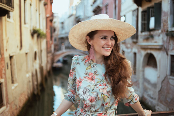 happy trendy woman in floral dress with hat exploring attractions in Venice, Italy. - Fotó, kép
