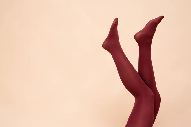 Woman raised up legs in the red stockings on the light background. - Фото, изображение