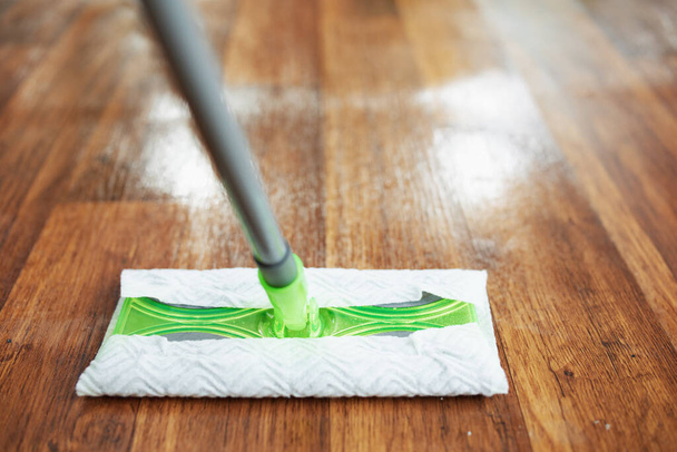 Household time. Closeup on mop and wet floor in the modern house in sunny day. - Photo, image
