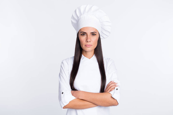 Zdjęcie skupione młoda dziewczyna skrzyżowane ręce wyglądają aparat nosić gotowanie czapki izolowane na białym tle koloru - Zdjęcie, obraz
