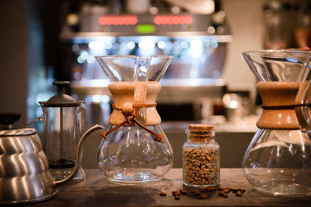 Кофейные зерна не жареные в банке с крышкой и некоторые жареные бобы  - Фото, изображение