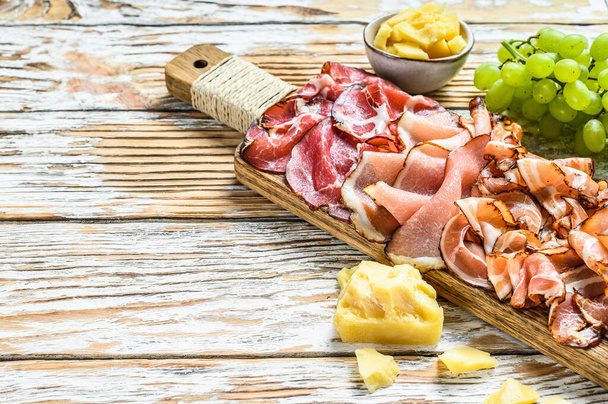 Set of cold cured italian meat Ham, prosciutto, pancetta, bacon. White wooden background. Top view. Copy space - Photo, Image