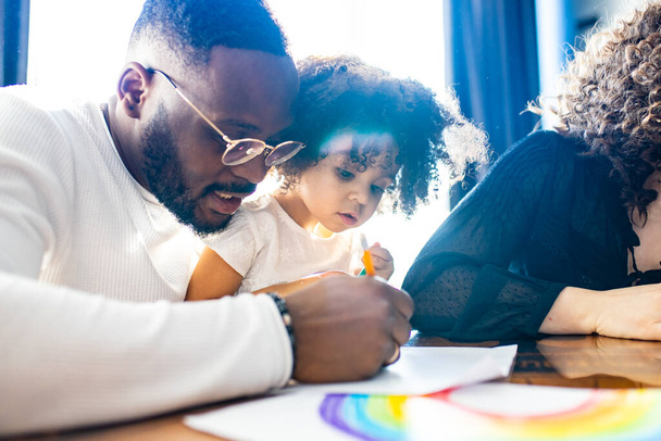 father wearing glasses and adorable little daughter drawing colorful pencils spending leisure time on weekend together - Foto, Imagen