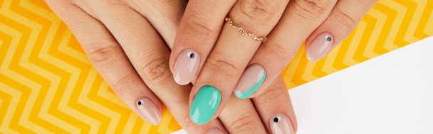 Beautiful groomed womans hands with trendy nail design on yellow background - Photo, Image