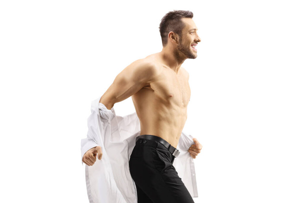 Handsome man taking off his shirt isolated on white background - Valokuva, kuva