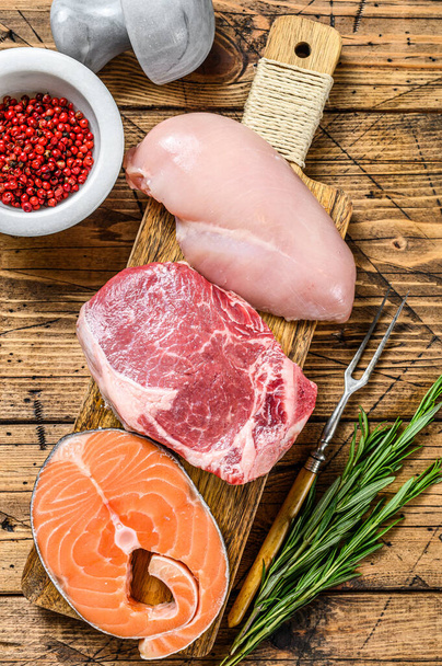 Animal protein sources meat, fish, and poultry. Raw steaks. wooden background. Top view - Photo, Image
