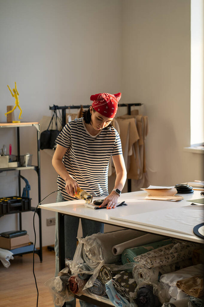Young creative girl designer cutting patterns for collection making in professional workshop studio - Fotografie, Obrázek