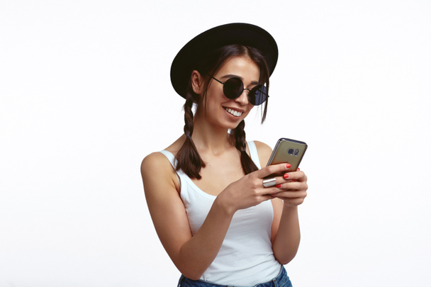 Dívka se slunečními brýlemi s úsměvem a pomocí webové služby s mobilním telefonem - Fotografie, Obrázek
