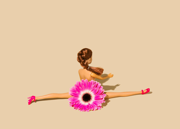 Tornász lány baba egy gyönyörű virág jelmez ül oldalán osztva bézs háttér helyet a szövegnek. Kreatív fitness koncepció.  - Fotó, kép