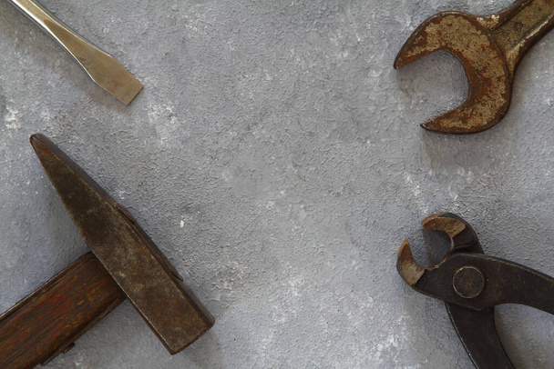 Hammer, Schraubenschlüssel, Handschuhe und andere abgenutzte und verschmutzte Werkzeuge auf Steingrund mit Kopierraum. Vatertag, Heimwerken, Heimwerken oder Arbeitstag Hintergrundkonzept. - Foto, Bild
