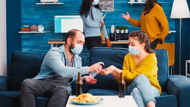 Gemengde rassen vrienden met medische maskers desinfecteren handen - Foto, afbeelding