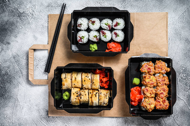 寿司のテイクアウトレストランで注文された配送パッケージには寿司が転がります。灰色の背景。トップ表示 - 写真・画像