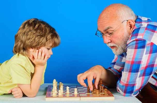 Grandson playing chess with grandpa. Grandfather teaching grandchild play chess. Family relationship. - 写真・画像