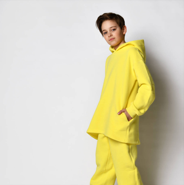 Full length portrait of a teenage boy dressed in a bright yellow sports suit. - Photo, image