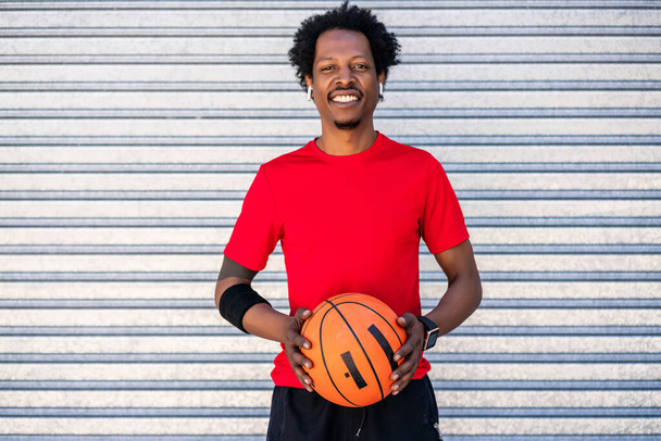 Afro athlète homme tenant un ballon de basket à l'extérieur. - Photo, image