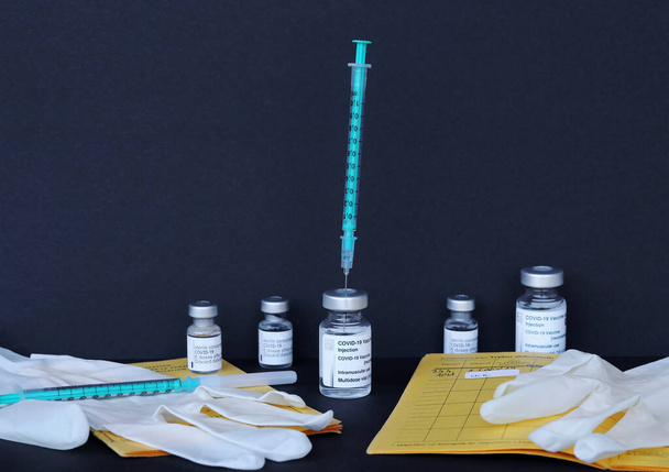 Εμβολιασμός με Corona Covid- 19 με κάρτα εμβολιασμού, φιάλες εμβολιασμού και σύριγγες  - Φωτογραφία, εικόνα