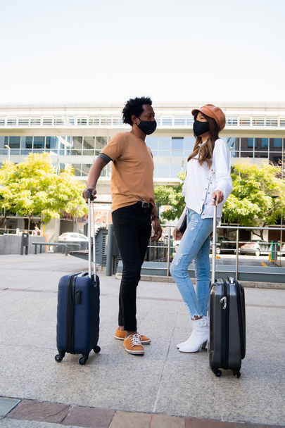 Tourist couple carrying suitcase outdoors. - Foto, Bild