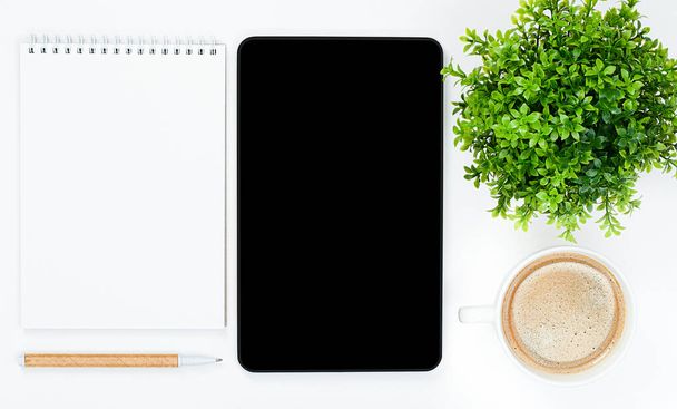 ordinateur portable, tablette, stylo, tasse à café et plante maison sur le bureau. vue de dessus. concept de télétravail - Photo, image