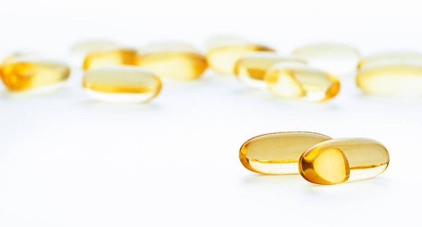 twee omega-3 capsules op de voorgrond, veel verstrooide capsules op de achtergrond - Foto, afbeelding