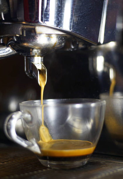 A vertical closeup of an espresso machine pouring fresh coffee in a cup - 写真・画像